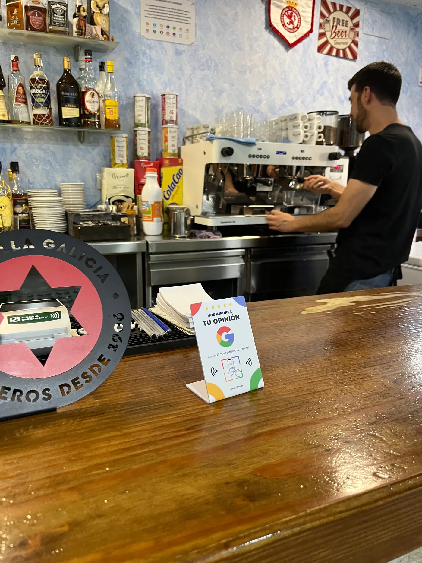 Expositor en la barra de un bar mientras el camarero prepara café